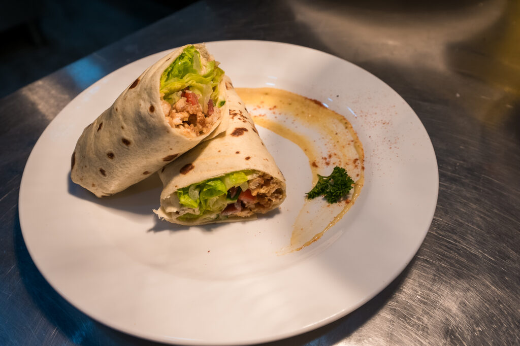 Wrap filled with fresh salad, served with dipping sauce